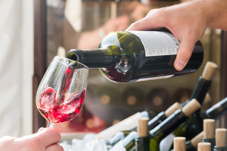 the red wine being poured into a glass close-upの写真素材