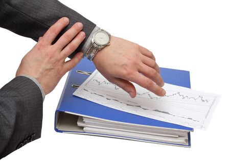 Hands of the chief with a clock on the background of a folder with documents and financial scheduleの写真素材