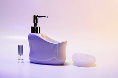 Liquid soap dispenser in a ceramic bath with a sponge and a spray jar, in purple night light
の写真素材