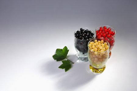 Currants of three colors in different glasses together on the surface. Delicious and healthy food...