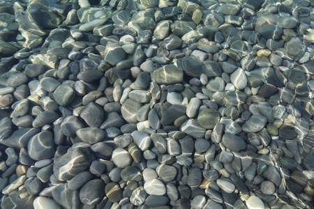 Top view of stones under water on shallow water on a sunny day in flat layの写真素材