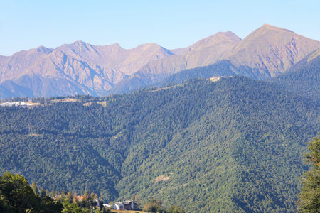 Green mountain landscape with houses at the bottom of the valley and ridge above on summer day with...