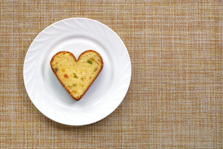 Cupcake in form of heart on white plate in flat lay with copy space