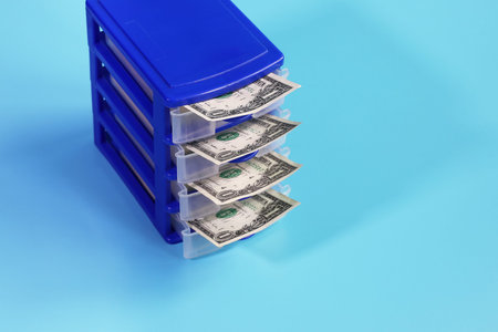 Box with open cells from which dollars are visible on blue background with copy space close-up
