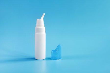 White bottle for spray inhalation on blue background with copy space