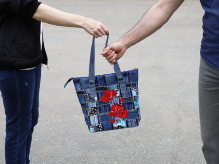 Men's hand take away jeans bag from woman, close-up