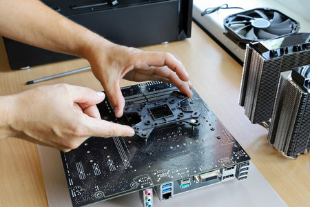Hands install backplate on back of motherboard for fastening cooler processor when assembling new...