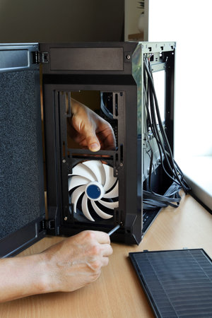 Hands screw cooling fan of computer case when assembling new PC