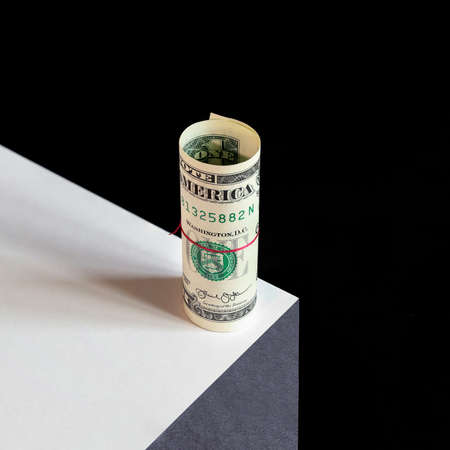 Concept twisted one american dollar stands on edge of abyss, on black background close-upの写真素材