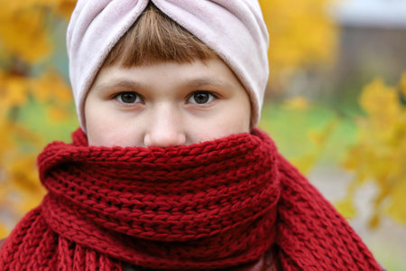 Girl wrapped in red scarf to be warm and looking into camera, close-up outdoorsの写真素材