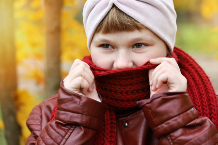 Girl wrapped in red scarf so that it was warm in autumn outdoors, close-up smiling faceの写真素材