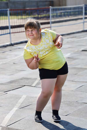 Girl with overweight in sportswear with smile posing for photo. She wants to do sports, but distractedの写真素材