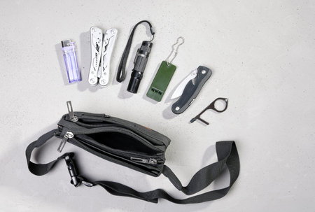 Wearable set for survival and tourism, every day carry, in flat lay on gray background