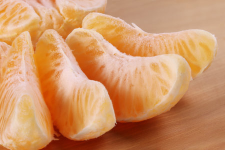 Juicy orange slices tangerine disconnected peel, close-up on a wooden surface