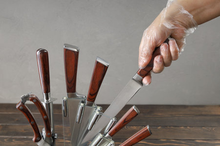 Male hand in transparent glove takes out knife from set to use it, close-up