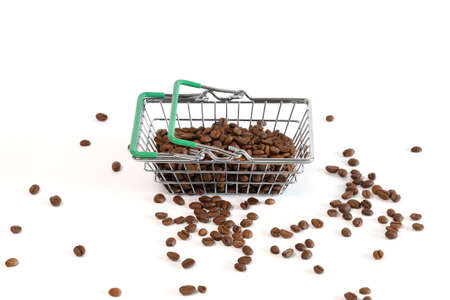 Coffee beans in goods basket and scattered on white surface with copy spaceの写真素材