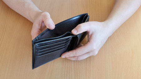 Empty open wallet without money inside, in hands of person close-up