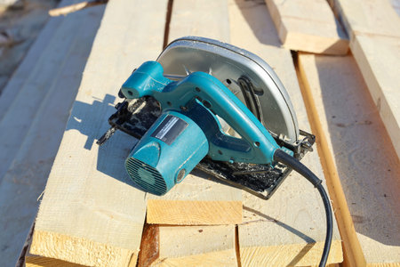 Power tool disc saw on lumber boards, real construction, outdoors close-up