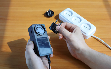 Human hands close-up hold plug of power supply adapter to change option of sockets for EU socket