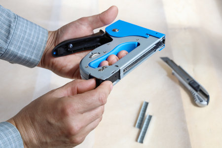 Hands open construction stapler to fill it with new staples for job, close-upの写真素材