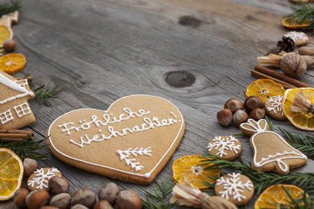 Heart shaped Christmas gingerbread with white icing, written in German, on wooden backgroundの写真素材