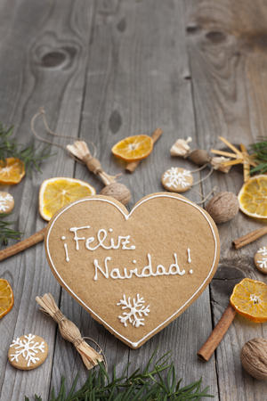 Heart shaped Christmas gingerbread with white icing,  on wooden background, written in Spanishの写真素材