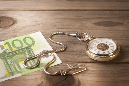 Retro clock and euro banknote on a wooden tableの写真素材