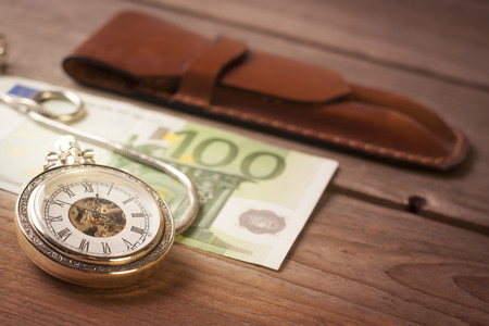 Retro clock and euro banknote on a wooden tableの写真素材