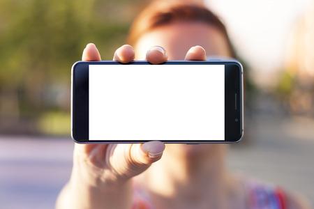 Woman hand holding contemporary modern smartphone. Visual effects. Blank display replaceable with needed design.Horizontal mockupの写真素材