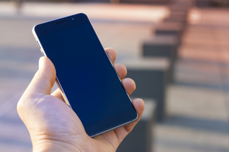 Man hand holding contemporary modern smartphone. Visual effects..Vertical mockupの写真素材