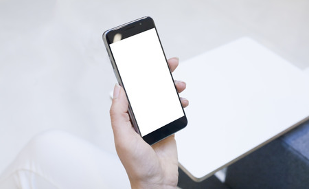 Woman hand holding contemporary modern smartphone. Visual effects. Blank display replaceable with needed design.Vertical mockupの写真素材
