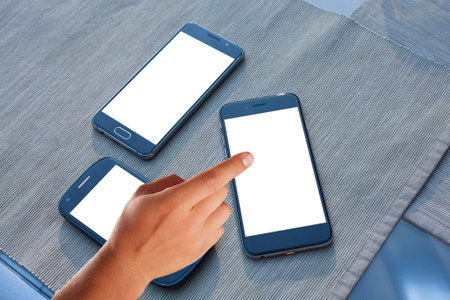 Modern smartphones.Finger pointing at screen. Blank display replaceable with needed design.Vertical...