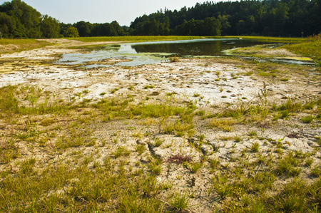 Polluted water and cracked soil of dried out lake during drought. の写真素材