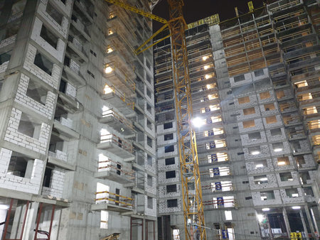 Construction of a multi-storey residential building in the evening in the dark bottom view. Cranes...