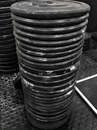 Black sports heavy pancakes inventory - weights from the rods folded in a row vertically on each other. Dumbbell from barbellsの写真素材