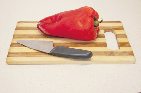 Red pepper and knife on a tableの写真素材