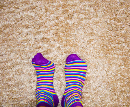 striped colored socks, legs on a soft matの写真素材