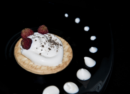 cookies with cream and strawberries on a black plateの写真素材