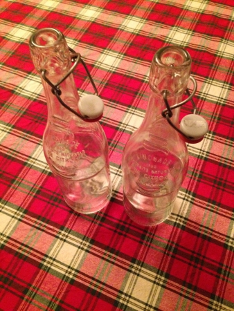 Two antique French water bottles on a plaid tableclothの素材
