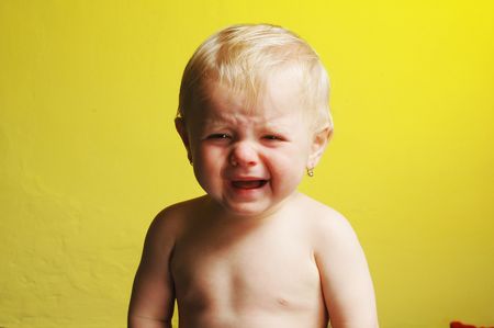 A crying little child on yellow backgroundの写真素材