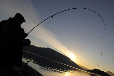 The sillhouette of fisherman with rod during te sunsetの写真素材
