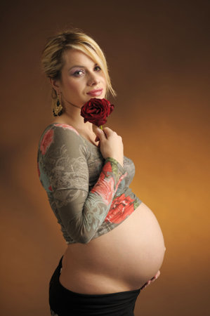 The portrait of attractive expectant mother with rose