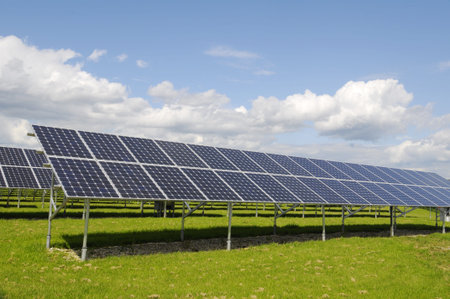 The black solar panels, green meadow and blue sky