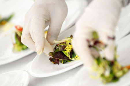 The hands with gum gloves preparing fresh vegetables on plate