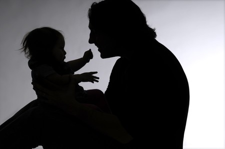 Shadow of a man holding a little girl on her kneesの写真素材