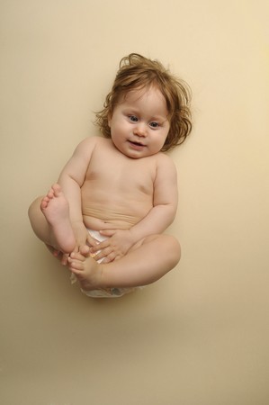 Little baby in diaper on beige backgroundの写真素材