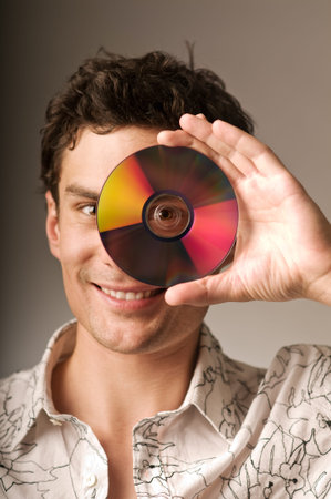 An young smiling man holding a compact disc