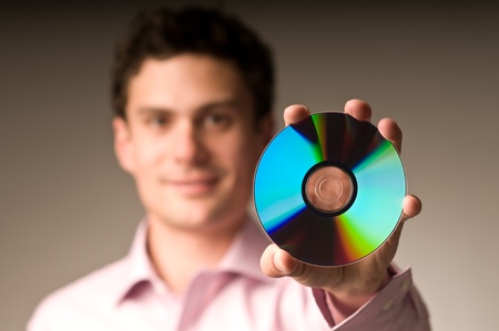 An young smiling man holding a compact discの写真素材