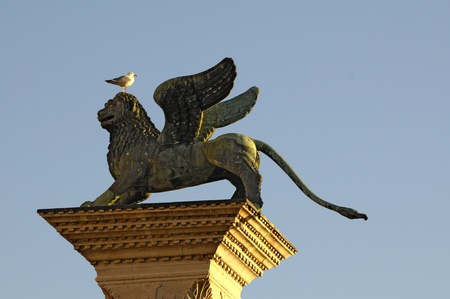 Picture of a stoned lion standing on the pole with a seagull on its headの写真素材