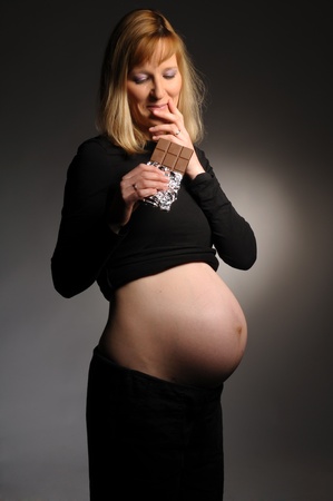 Picture of a young pregnant woman holding chocolate in her handの写真素材